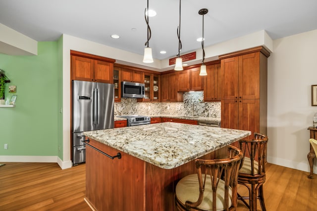 2611 Kiahuna Plantation Dr Unit 13D, Koloa, HI 96756 - kitchen with appliances with stainless steel finishes, wood finished floors, decorative backsplash, light stone counters, and baseboards