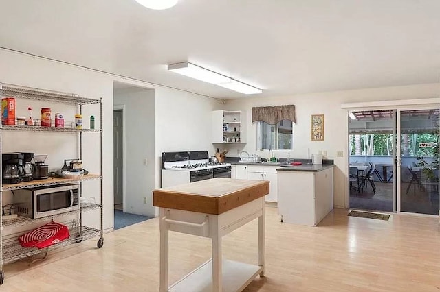 81-2026 Haku Nui Rd, Captain Cook, HI 96704 - kitchen with white gas range, open shelves, white cabinets, a sink, and light wood-type flooring