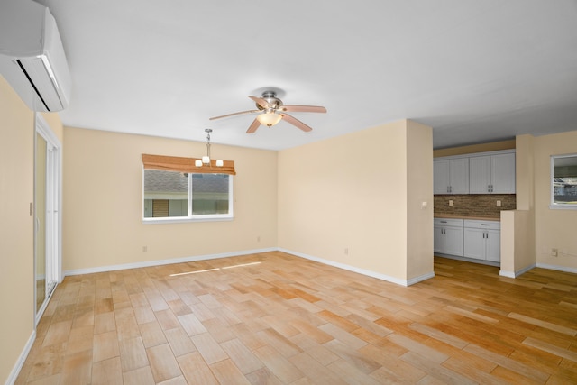 5372 Kumole St, Kapaa, HI 96746 - unfurnished living room with a wall mounted air conditioner, ceiling fan, light wood-style floors, a chandelier, and baseboards