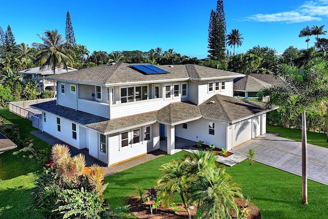 4576 Emmalani Dr, Princeville, HI 96722 - rear view of property with a garage, roof mounted solar panels, a shingled roof, driveway, and a yard