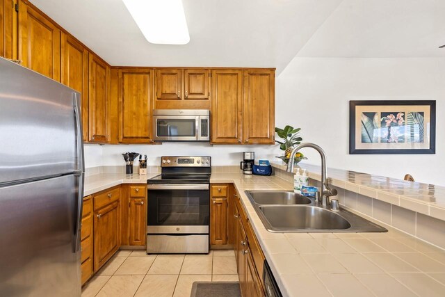 1565 Pee Rd Unit 221, Koloa, HI 96756 - kitchen with stainless steel appliances, a sink, tile counters, light tile patterned floors, and brown cabinetry