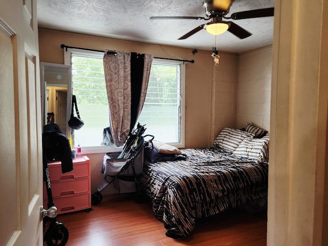 272 Kapiolani St Unit 203, Hilo, HI 96720 - bedroom with wood finished floors, a ceiling fan, a textured ceiling, and concrete block wall