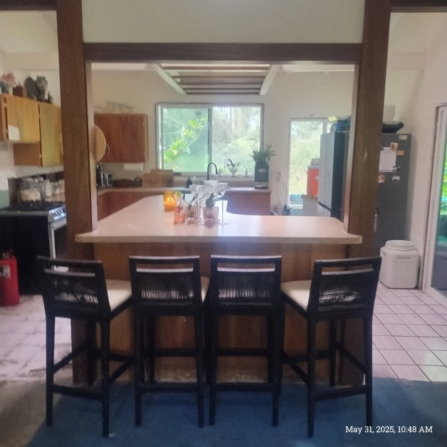 13-3313 Moku St, Pahoa, HI 96778 - kitchen featuring light countertops, freestanding refrigerator, a breakfast bar, and light tile patterned floors