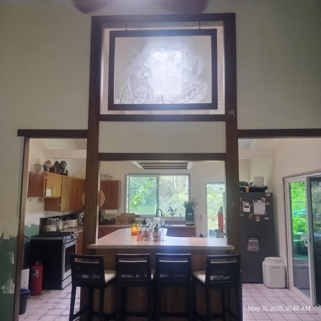 13-3313 Moku St, Pahoa, HI 96778 - kitchen with gas range, light tile patterned floors, a towering ceiling, and freestanding refrigerator