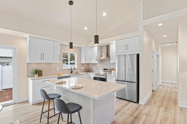 16-2068 Bamboo Dr, Pahoa, HI 96778 - kitchen with stainless steel appliances, wall chimney range hood, light wood-style floors, decorative backsplash, and a breakfast bar