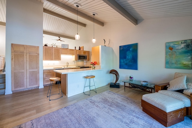 78-7039 Kamehameha Iii Rd Unit 148, Kailua-Kona, HI 96740 - kitchen with stainless steel microwave, a sink, a breakfast bar area, light wood-style flooring, and light countertops