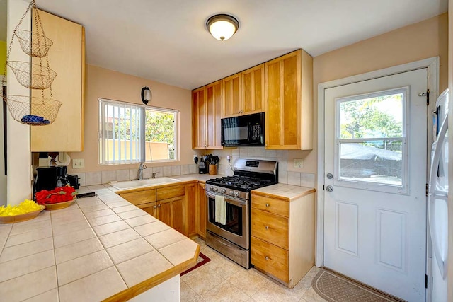 12-7036 Kaiwa St, Pahoa, HI 96778 - kitchen with gas stove, black microwave, tile counters, a sink, and white refrigerator with ice dispenser