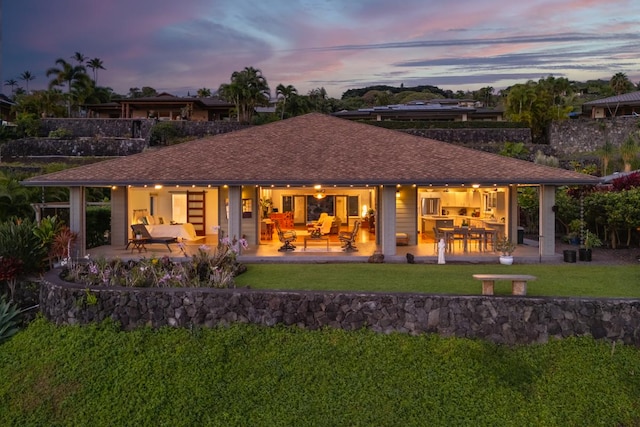 76-4391 Leilani St, Kailua-Kona, HI 96740 - back of property at dusk featuring a yard, an outdoor hangout area, a patio area, and roof with shingles