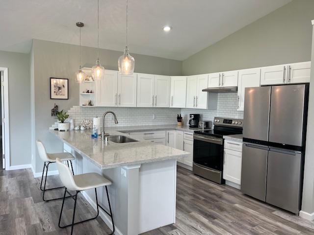 16-553 Orchidland Dr, Kurtistown, HI 96760 - kitchen with stainless steel appliances, lofted ceiling, a peninsula, under cabinet range hood, and a breakfast bar area