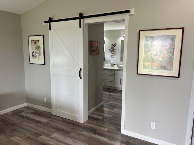 16-553 Orchidland Dr, Kurtistown, HI 96760 - unfurnished bedroom featuring dark wood-style floors, a barn door, vaulted ceiling, and ensuite bath