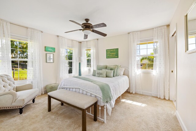 3764 Kakela Makai Dr, Kalaheo, HI 96741 - bedroom featuring multiple windows, light carpet, a ceiling fan, and baseboards