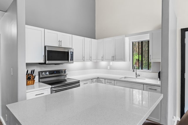 11-3827 5th St, Volcano, HI 96785 - kitchen with appliances with stainless steel finishes, a sink, a towering ceiling, a kitchen island, and white cabinets