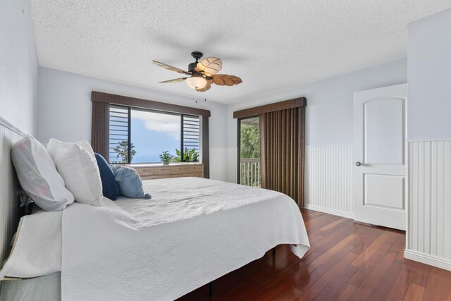 73-4332 Imo Pl, Kailua-Kona, HI 96740 - bedroom with dark wood-type flooring, a ceiling fan, a textured ceiling, and a wainscoted wall