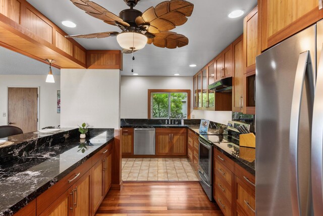 73-4332 Imo Pl, Kailua-Kona, HI 96740 - kitchen with appliances with stainless steel finishes, brown cabinetry, light wood-type flooring, under cabinet range hood, and dark stone countertops