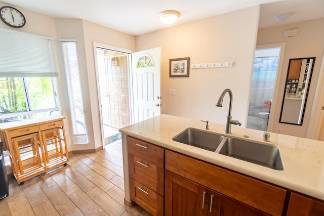 75-6081 Alii Dr Unit Kk102, Kailua-Kona, HI 96740 - kitchen featuring a sink, light wood-style flooring, light stone counters, and brown cabinets