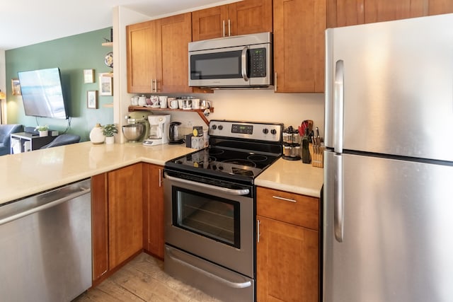 75-6081 Alii Dr Unit Kk102, Kailua-Kona, HI 96740 - kitchen featuring stainless steel appliances, light countertops, brown cabinets, light wood finished floors, and open floor plan