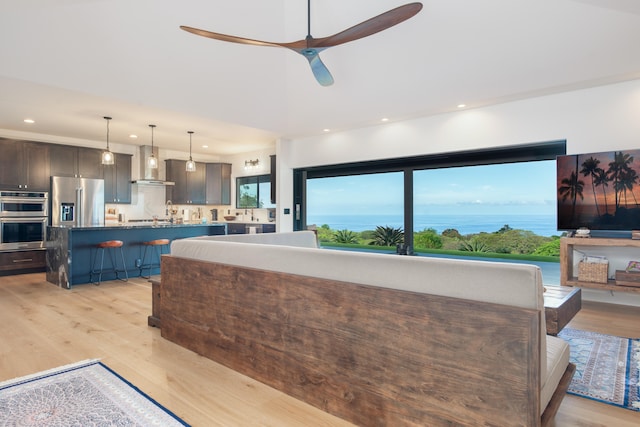 75-650 Halewili Pl, Kailua-Kona, HI 96725 - kitchen featuring stainless steel appliances, wall chimney exhaust hood, a breakfast bar, light wood-style floors, and recessed lighting