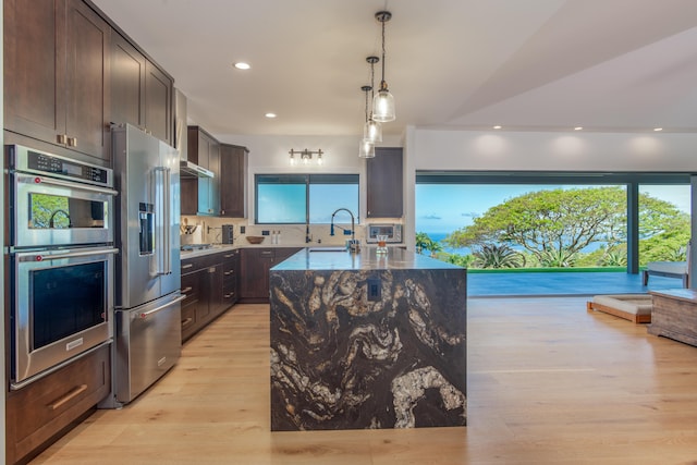 75-650 Halewili Pl, Kailua-Kona, HI 96725 - kitchen with stainless steel appliances, dark brown cabinetry, light wood-style flooring, a center island with sink, and recessed lighting