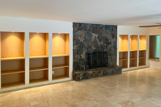 78-7259 Puuloa Rd, Kailua-Kona, HI 96740 - unfurnished living room featuring ceiling fan, a textured ceiling, a stone fireplace, stone tile flooring, and built in shelves