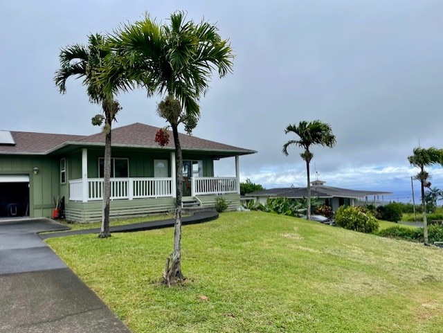 94-1654 Lewa Nuu St, Naalehu, HI 96772 - view of front of property featuring covered porch, board and batten siding, an attached garage, driveway, and a front lawn