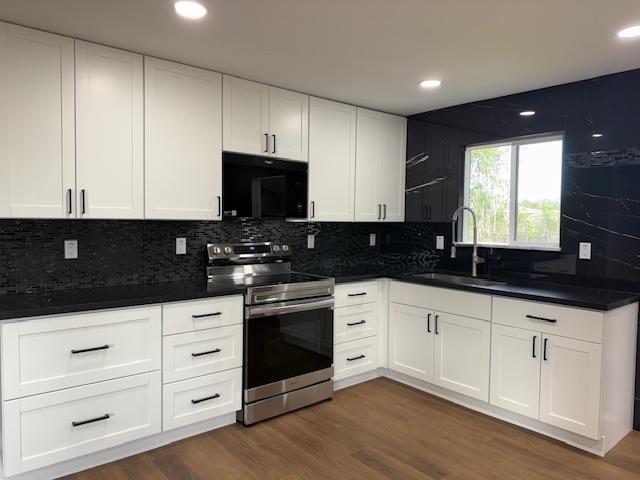 144 Chong St, Hilo, HI 96720 - kitchen with stainless steel range with electric stovetop, black microwave, dark countertops, and recessed lighting