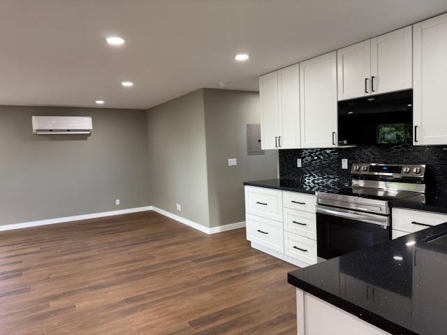 144 Chong St, Hilo, HI 96720 - kitchen with stainless steel range with electric stovetop, black microwave, a wall mounted AC, dark wood-style floors, and recessed lighting