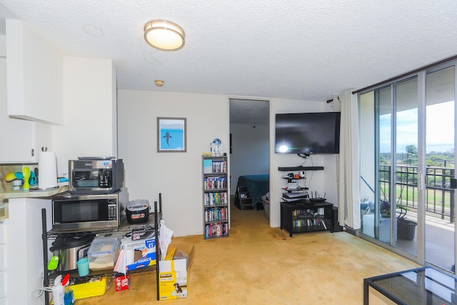 2916 Date St Unit 6F, Honolulu, HI 96816 - kitchen with stainless steel microwave, light carpet, a textured ceiling, expansive windows, and white cabinetry