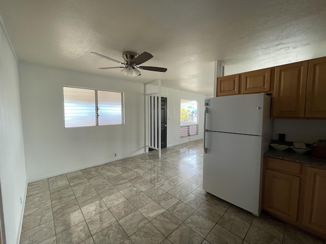 4548 Kawailoa St, Kekaha, HI 96752 - kitchen featuring freestanding refrigerator, ceiling fan, a textured ceiling, and brown cabinets
