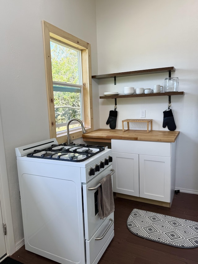 94 Pele St, Naalehu, HI 96772 - kitchen with white gas range oven, butcher block countertops, open shelves, white cabinets, and dark wood-style floors