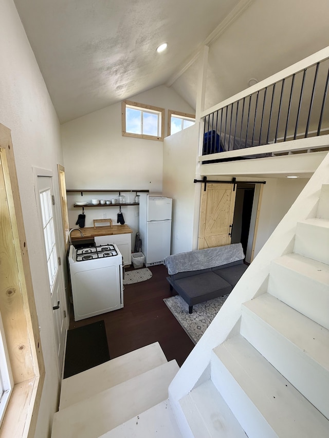 94 Pele St, Naalehu, HI 96772 - stairway featuring a barn door, high vaulted ceiling, washer / clothes dryer, and wood finished floors