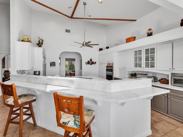 59-380 Olomana Rd, Kamuela, HI 96743 - kitchen featuring arched walkways, high vaulted ceiling, a kitchen breakfast bar, double oven, and a peninsula