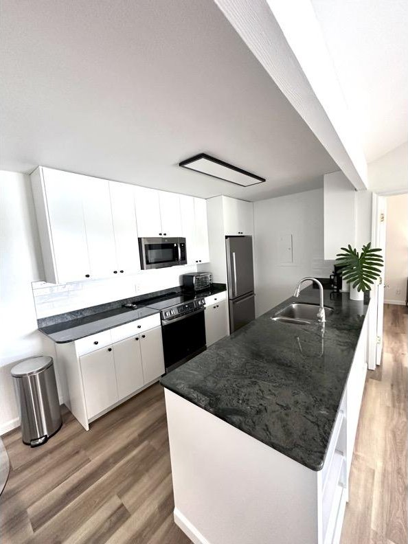 68-3883 Lua Kula St Unit 707, Waikoloa, HI 96738 - kitchen with stainless steel appliances, a peninsula, wood finished floors, dark countertops, and white cabinets
