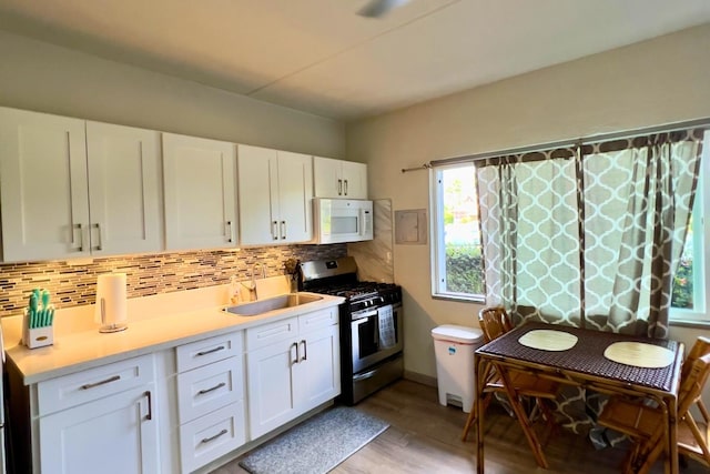 50 Maile St Unit A3, Hilo, HI 96720 - kitchen featuring white microwave, stainless steel gas range oven, light wood-type flooring, decorative backsplash, and light countertops