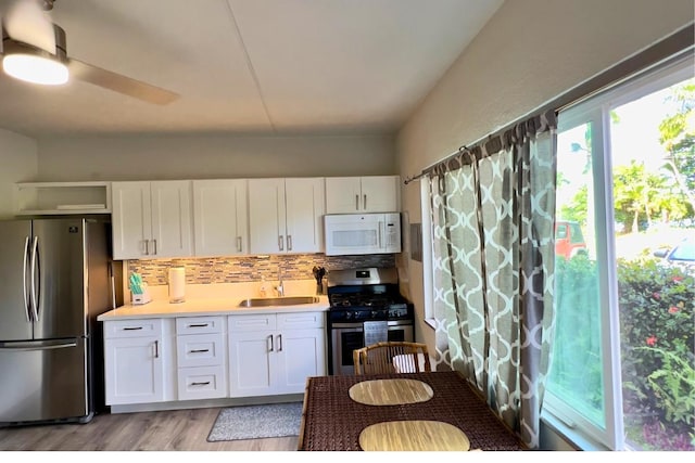50 Maile St Unit A3, Hilo, HI 96720 - kitchen featuring appliances with stainless steel finishes, backsplash, white cabinetry, and light wood-style floors