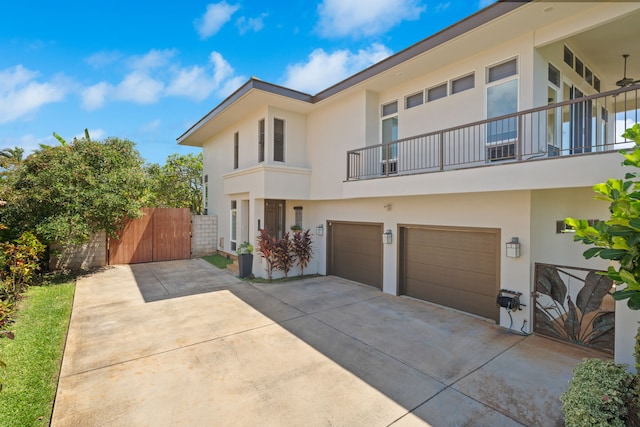 1690 Keleka Rd, Koloa, HI 96756 - view of front of house featuring driveway, stucco siding, a balcony, an attached garage, and a gate