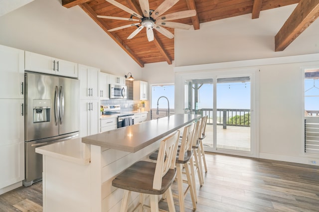 77-6452 Leilani St, Kailua-Kona, HI 96740 - kitchen featuring appliances with stainless steel finishes, light wood finished floors, an island with sink, a ceiling fan, and a breakfast bar area