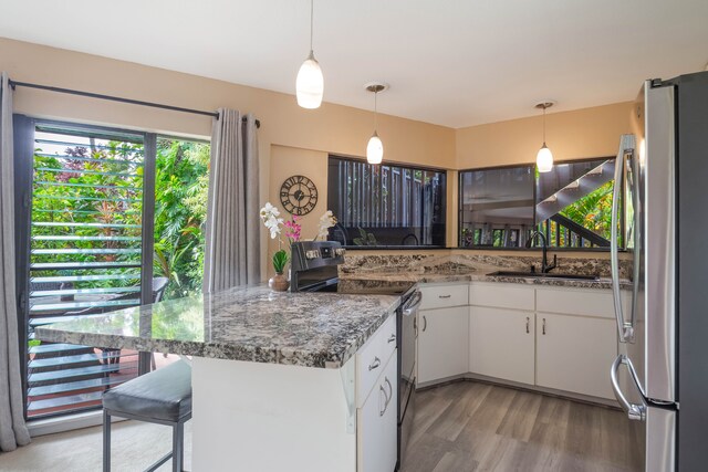 3920 Wyllie Rd Unit 6A, Princeville, HI 96722 - kitchen featuring stainless steel appliances, white cabinetry, light wood-style floors, a peninsula, and hanging light fixtures