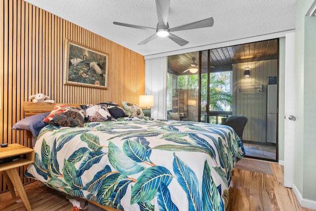 77-301 Noelani Way Unit 12, Kailua-Kona, HI 96740 - bedroom featuring wood finished floors, wooden walls, access to outside, a ceiling fan, and a textured ceiling
