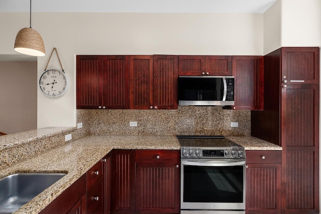 69-200 Pohakulana Pl Unit E2, Waikoloa, HI 96738 - kitchen featuring stainless steel appliances, reddish brown cabinets, decorative light fixtures, light stone countertops, and decorative backsplash