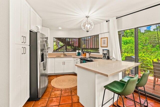 3920 Wyllie Rd Unit 10A, Princeville, HI 96722 - kitchen featuring appliances with stainless steel finishes, a peninsula, white cabinets, a chandelier, and light countertops