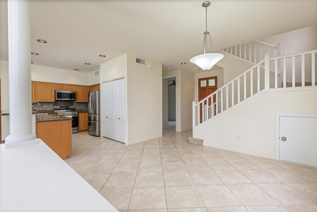 75-6060 Kuakini Hwy Unit E4, Kailua-Kona, HI 96740 - kitchen featuring stainless steel appliances, brown cabinetry, tasteful backsplash, dark countertops, and light tile patterned flooring