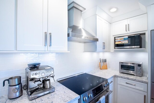 1565 Pee Rd Unit 122, Koloa, HI 96756 - kitchen with wall chimney range hood, stainless steel electric range, backsplash, and white cabinetry