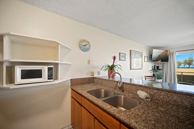 525 Aleka Lp Unit F15, Kapaa, HI 96746 - kitchen with white microwave, brown cabinetry, a textured ceiling, and dark stone countertops
