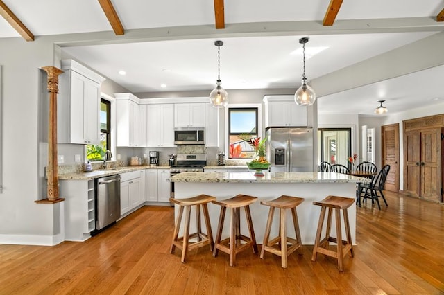 5414 Nakoa St, Koloa, HI 96756 - kitchen featuring stainless steel appliances, a center island, beam ceiling, white cabinetry, and a breakfast bar