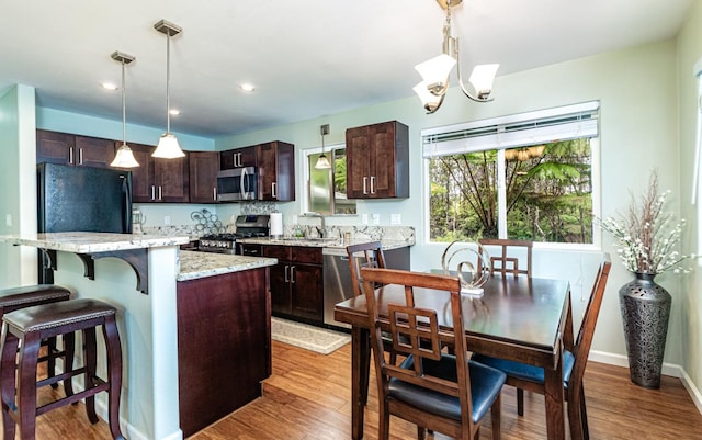 11-3082 Pa Alii St, Volcano, HI 96785 - kitchen with appliances with stainless steel finishes, dark brown cabinetry, a kitchen bar, decorative light fixtures, and wood finished floors