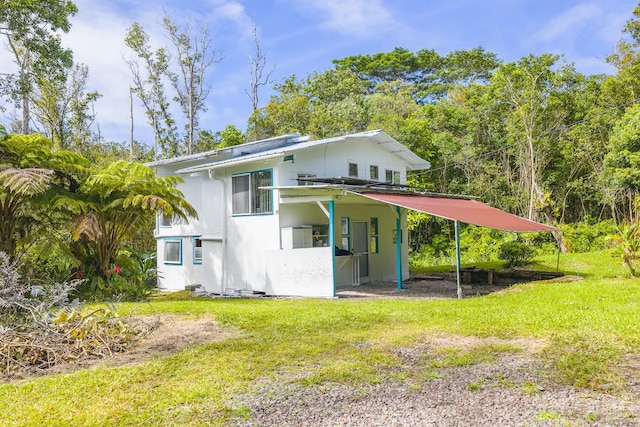 12-557 Hawaii St, Pahoa, HI 96778 - rear view of house featuring a lawn, a carport, and stucco siding