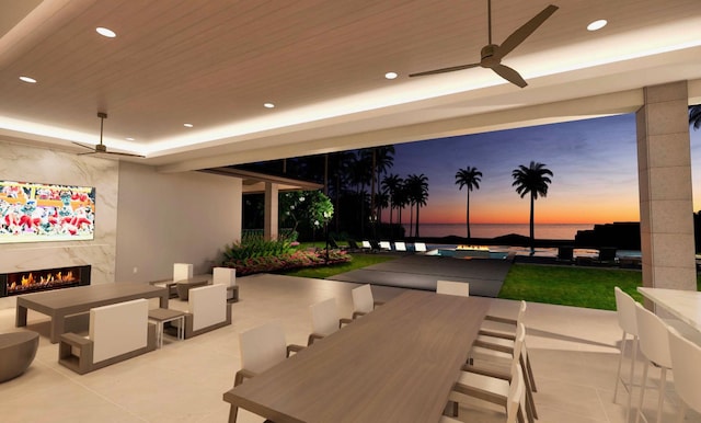 68-1006 Ke Kailani Dr, Kamuela, HI 96743 - patio terrace at dusk featuring outdoor dining space, a patio area, a fireplace, and a water view