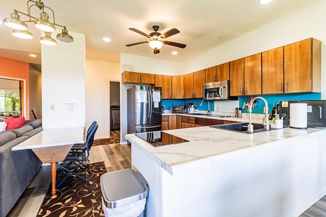 28-238 Akaka Falls Rd, Honomu, HI 96728 - kitchen with stainless steel appliances, a peninsula, light wood finished floors, brown cabinets, and recessed lighting