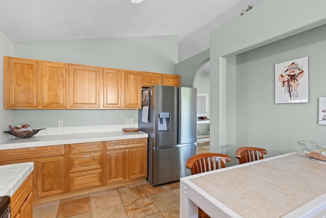55-548 Hawi Rd, Hawi, HI 96719 - kitchen with stainless steel fridge, lofted ceiling, tile countertops, arched walkways, and light stone finish floors