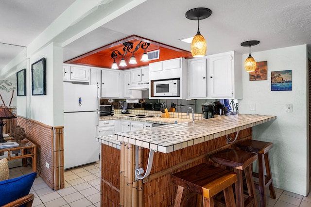 75-6082 Alii Dr Unit A207, Kailua-Kona, HI 96740 - kitchen with white appliances, a peninsula, under cabinet range hood, and white cabinetry